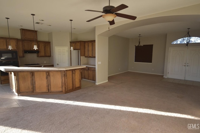 kitchen with light carpet, tasteful backsplash, brown cabinets, fridge, and black microwave