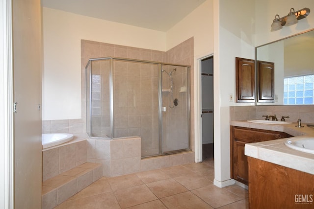 full bathroom with a walk in closet, double vanity, a sink, a shower stall, and tile patterned flooring