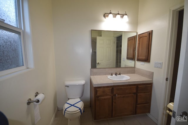 bathroom featuring toilet, vanity, baseboards, and tile patterned floors