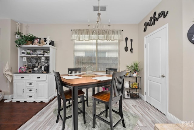 dining space with baseboards, visible vents, an inviting chandelier, and wood finished floors