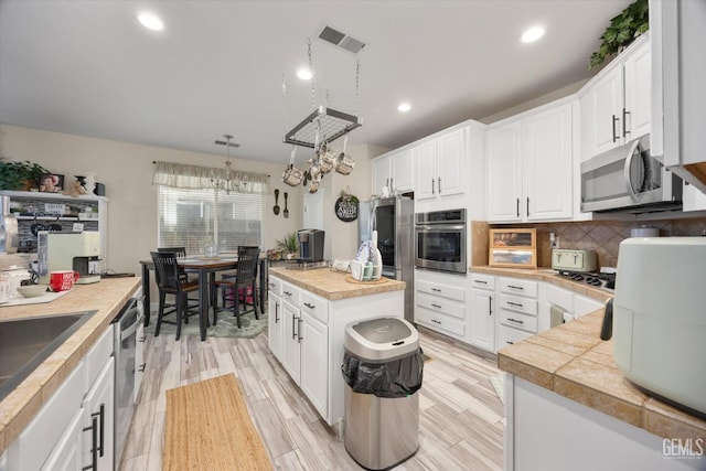 kitchen featuring stainless steel appliances, tile counters, and white cabinets