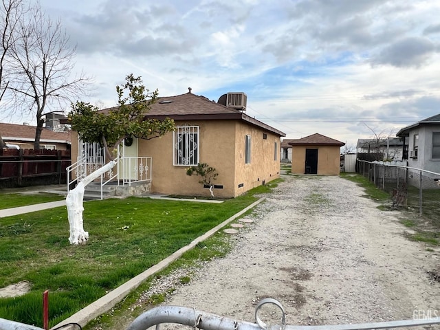 bungalow-style house featuring central AC, an outbuilding, and a front yard