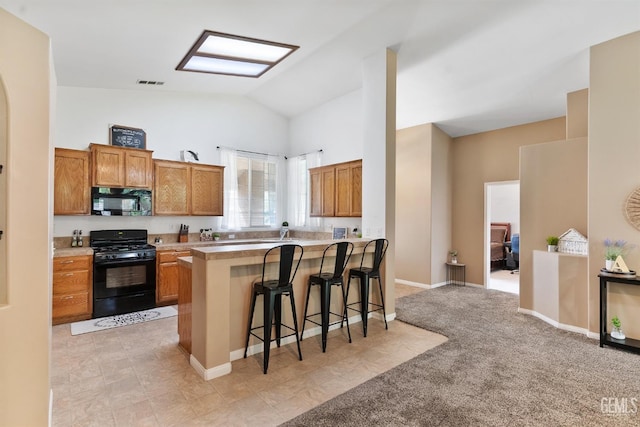 kitchen with a breakfast bar, light countertops, brown cabinets, a peninsula, and black appliances