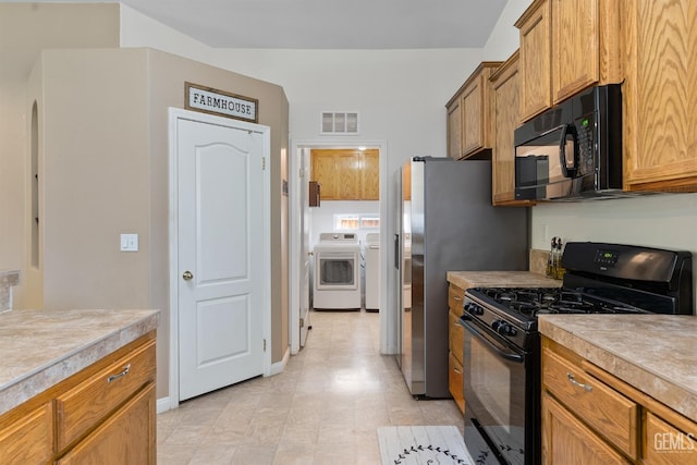 kitchen with visible vents, washer and dryer, black appliances, and light countertops