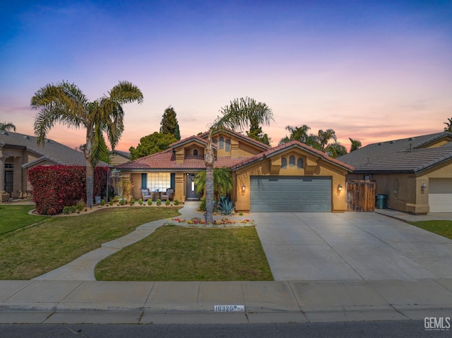 view of front of property featuring stucco siding, a tile roof, a yard, concrete driveway, and a garage