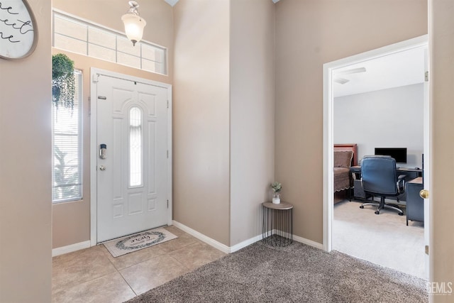 carpeted foyer featuring baseboards and tile patterned flooring