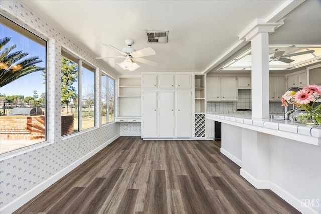 interior space with ceiling fan, tile counters, dark hardwood / wood-style flooring, and decorative backsplash