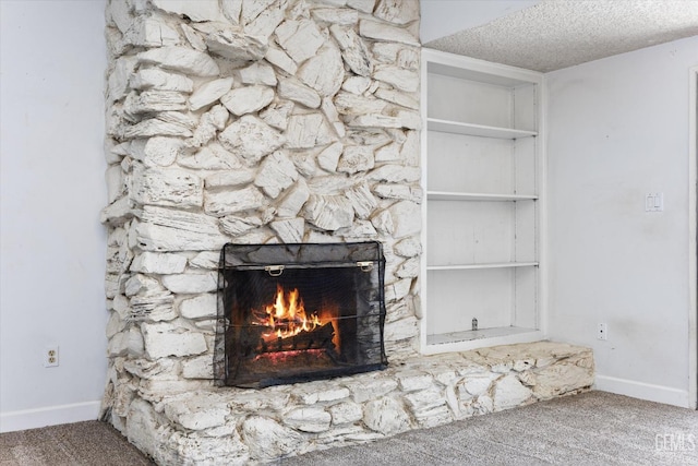 interior details featuring carpet floors, built in shelves, and a stone fireplace