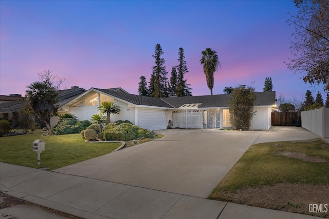 ranch-style house with a garage and a lawn