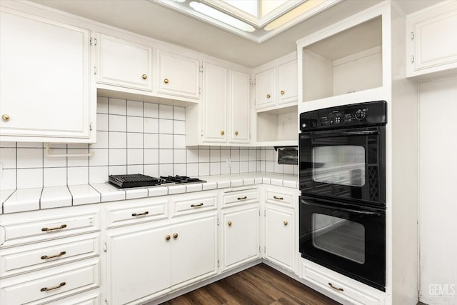 kitchen featuring white cabinets, black double oven, gas stovetop, and tile counters