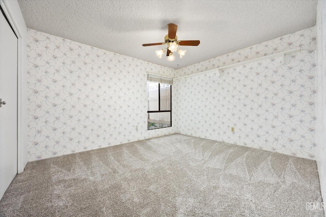 unfurnished room featuring a textured ceiling, ceiling fan, and carpet floors