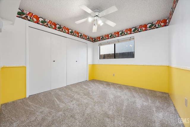 unfurnished bedroom featuring a textured ceiling, ceiling fan, a closet, and carpet floors