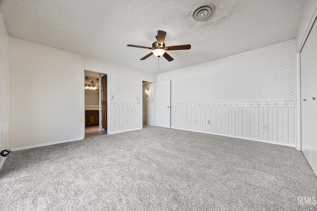 unfurnished bedroom featuring carpet flooring, a textured ceiling, connected bathroom, ceiling fan, and a closet