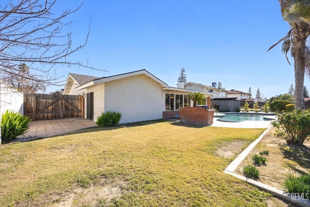 rear view of house with a yard and a fenced in pool