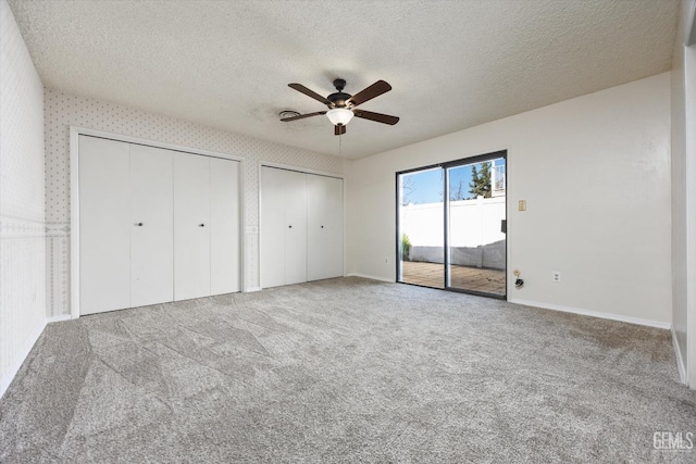 unfurnished bedroom with ceiling fan, access to outside, a textured ceiling, and carpet flooring