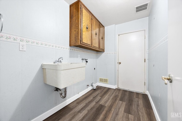 washroom featuring sink, dark hardwood / wood-style flooring, washer hookup, and cabinets