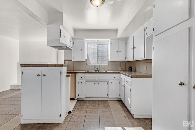 kitchen featuring light tile patterned floors, backsplash, white cabinets, and tile counters