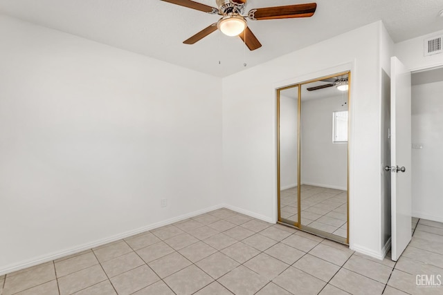 unfurnished bedroom featuring light tile patterned flooring, a closet, and ceiling fan