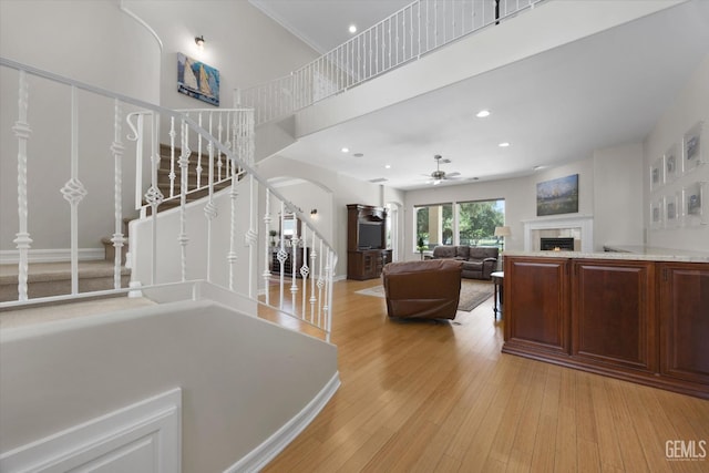 2120 Wedgemont Pl, Bakersfield, CA 93311 - living area featuring stairway, a tiled fireplace, ceiling fan, arched walkways, and light wood-style floors