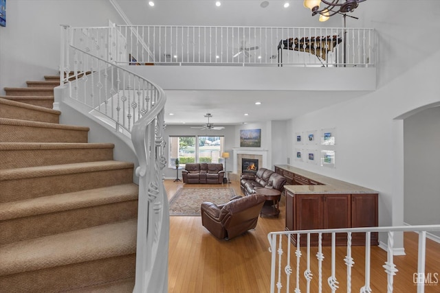 2120 Wedgemont Pl, Bakersfield, CA 93311 - living area with a ceiling fan, a high ceiling, wood finished floors, a tiled fireplace, and stairs