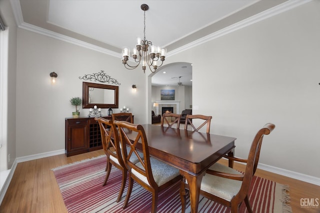 2120 Wedgemont Pl, Bakersfield, CA 93311 - dining area with arched walkways, light wood finished floors, a lit fireplace, crown molding, and a chandelier