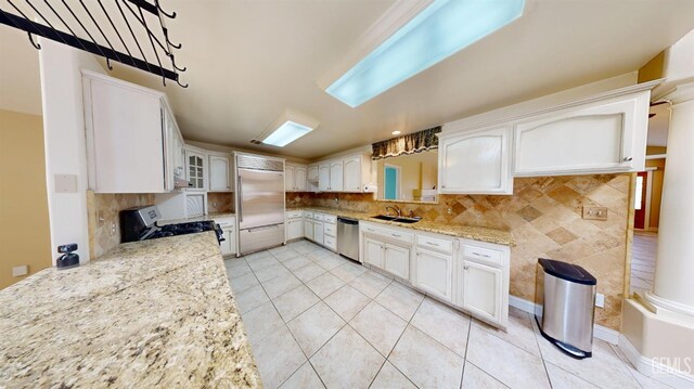 1334 Renfro Rd, Bakersfield, CA 93314 - kitchen with appliances with stainless steel finishes, a sink, tasteful backsplash, white cabinets, and light tile patterned floors