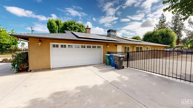 1334 Renfro Rd, Bakersfield, CA 93314 - view of front of home featuring an attached garage, stucco siding, solar panels, fence, and driveway