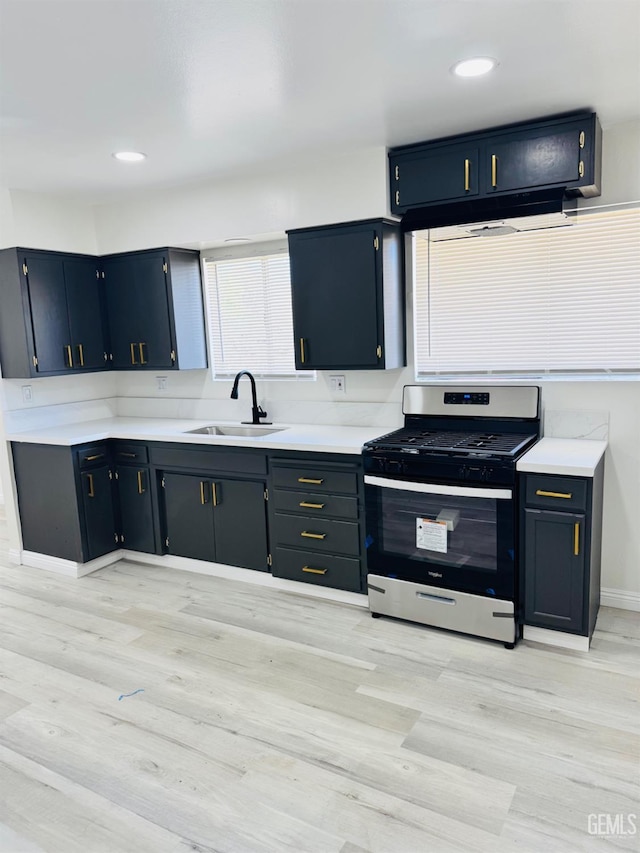 123 Ferguson Ave, Bakersfield, CA 93308 - kitchen featuring light countertops, stainless steel range with gas stovetop, a sink, and light wood finished floors
