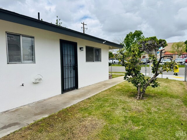 123 Ferguson Ave, Bakersfield, CA 93308 - view of exterior entry featuring a lawn, fence, and stucco siding