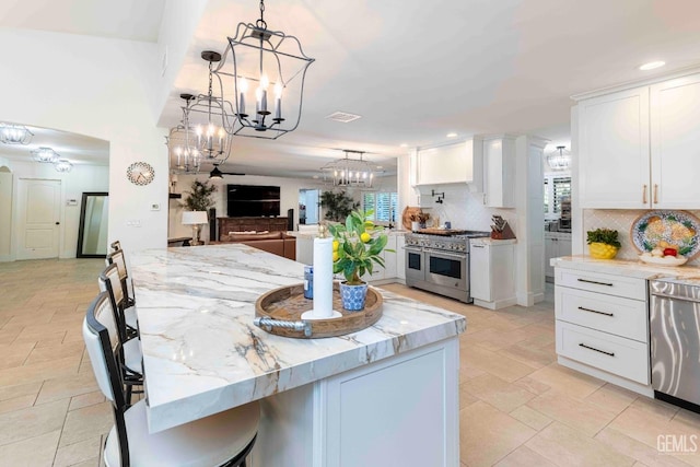 854 Vineland Rd, Bakersfield, CA 93306 - kitchen featuring appliances with stainless steel finishes, a chandelier, decorative backsplash, light stone counters, and white cabinetry