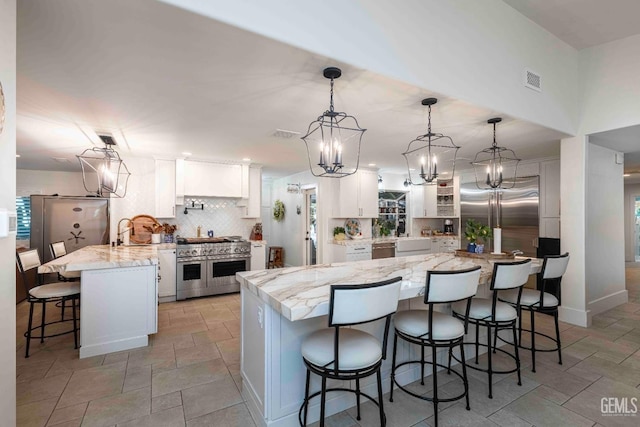 854 Vineland Rd, Bakersfield, CA 93306 - kitchen featuring high end appliances, a kitchen bar, white cabinets, stone tile flooring, and decorative backsplash