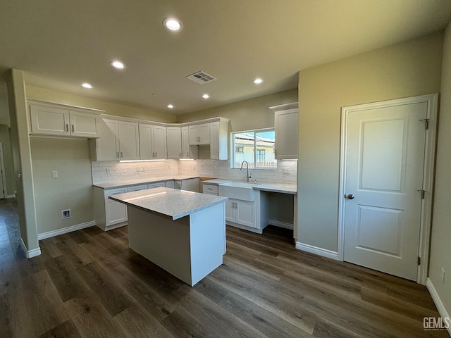 kitchen featuring a center island, white cabinets, dark wood-type flooring, and sink