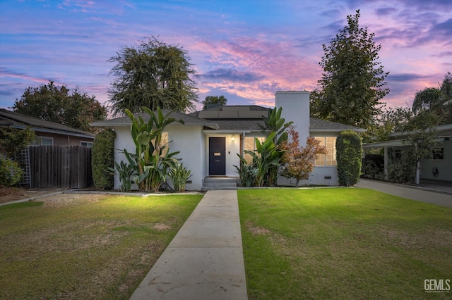 view of front of property with solar panels and a yard