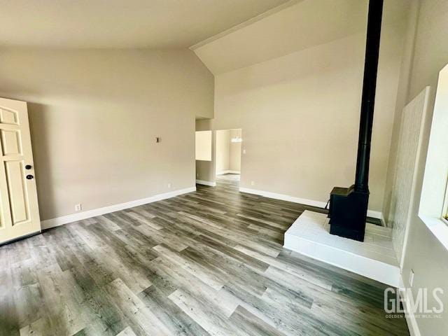 unfurnished living room featuring a wood stove, baseboards, and wood finished floors