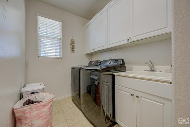 clothes washing area featuring washer and dryer, light tile patterned floors, cabinets, and sink