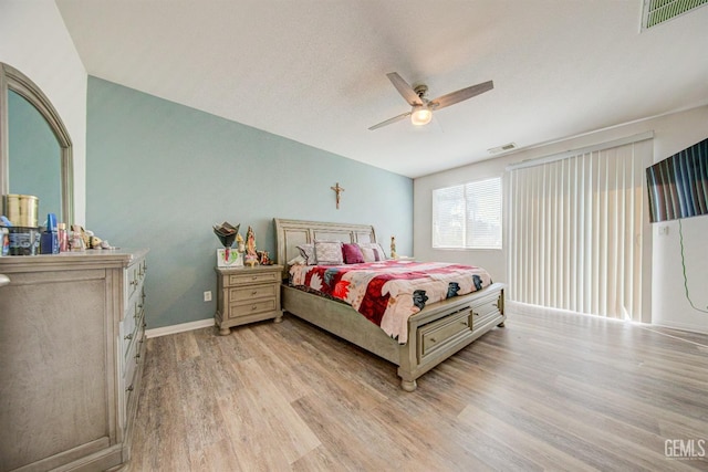 bedroom featuring ceiling fan, light hardwood / wood-style floors, and a textured ceiling