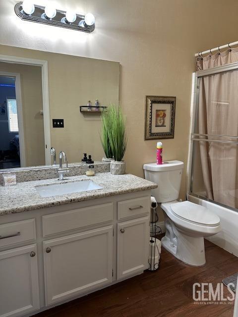 full bathroom with vanity, hardwood / wood-style flooring, shower / bath combination with curtain, and toilet