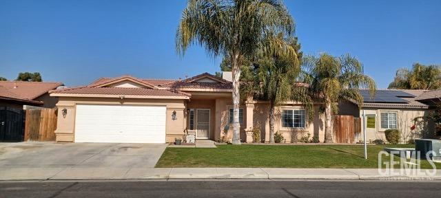 single story home with a front yard, a garage, and solar panels