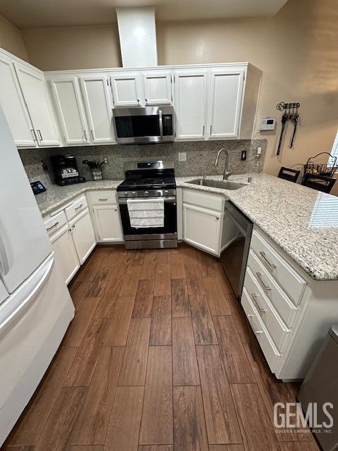 kitchen with white cabinets, appliances with stainless steel finishes, decorative backsplash, sink, and kitchen peninsula