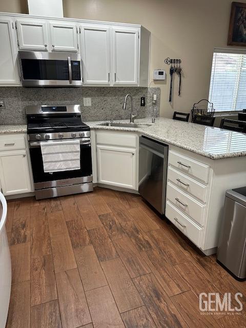 kitchen with sink, white cabinetry, kitchen peninsula, and appliances with stainless steel finishes