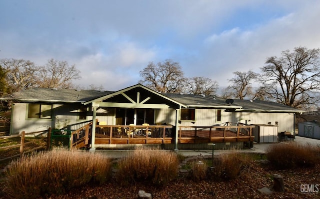 rear view of property with a storage unit and a deck