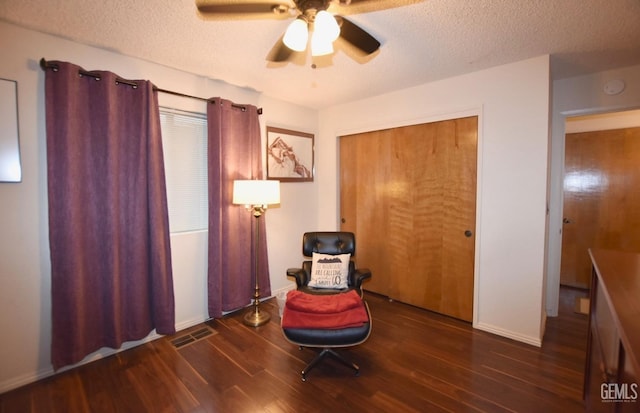 sitting room with a textured ceiling, dark hardwood / wood-style floors, and ceiling fan