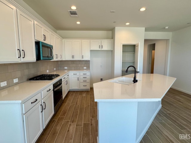 2411 Addlington St, Bakersfield, CA 93311 - kitchen featuring oven, gas cooktop, dark wood-style floors, a kitchen island with sink, and recessed lighting