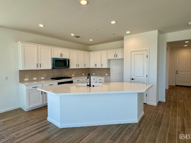 2411 Addlington St, Bakersfield, CA 93311 - kitchen featuring stainless steel microwave, dark wood-type flooring, a center island with sink, light countertops, and recessed lighting