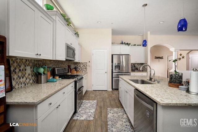 9311 Caliente Creek Ct, Bakersfield, CA 93311 - kitchen featuring stainless steel appliances, arched walkways, white cabinetry, tasteful backsplash, and recessed lighting