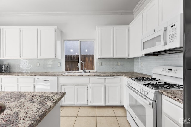 kitchen with white appliances, a sink, white cabinetry, and light stone countertops