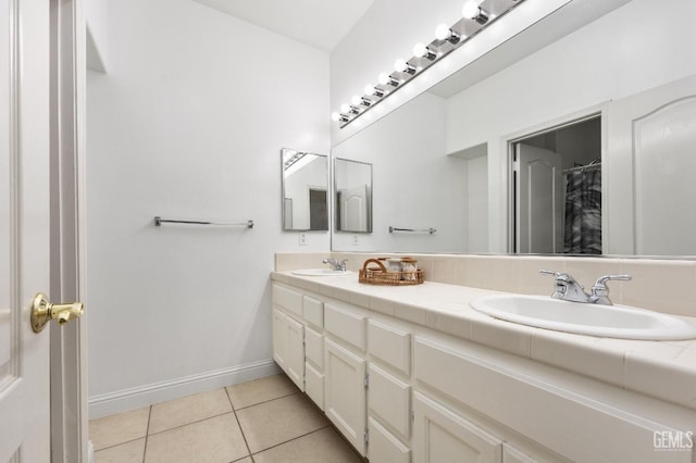 bathroom with tile patterned flooring, a sink, baseboards, and double vanity