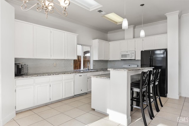 kitchen with white appliances, visible vents, a center island, hanging light fixtures, and white cabinetry