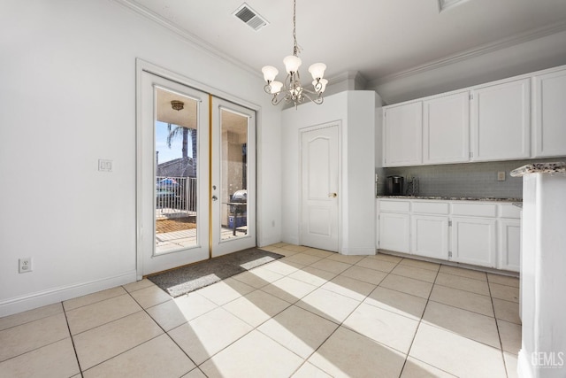 unfurnished dining area with light tile patterned flooring, crown molding, visible vents, and an inviting chandelier