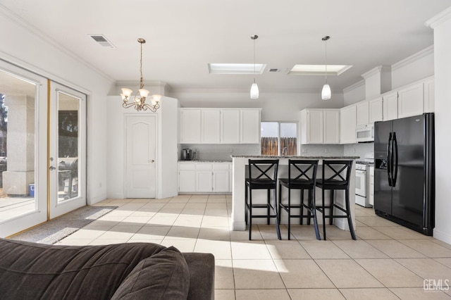 kitchen with a breakfast bar area, white appliances, visible vents, white cabinetry, and a center island